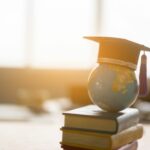 Academische hoed op stapel boeken en wereldbol